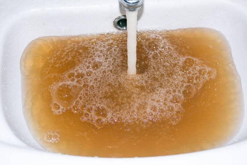 Brown well water flowing from faucet