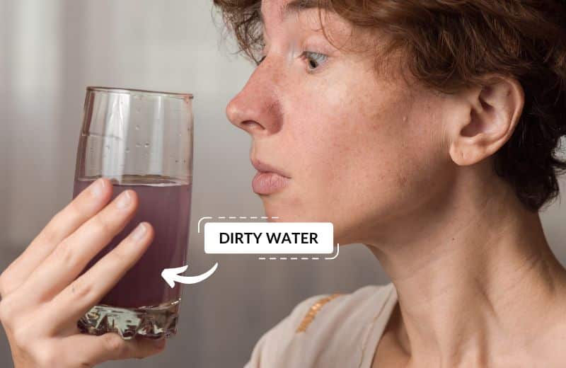 Person holding a glass of dirty water