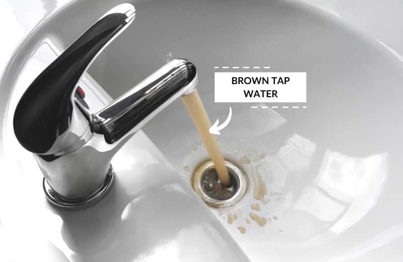 Yellow tap water flowing in a sink.