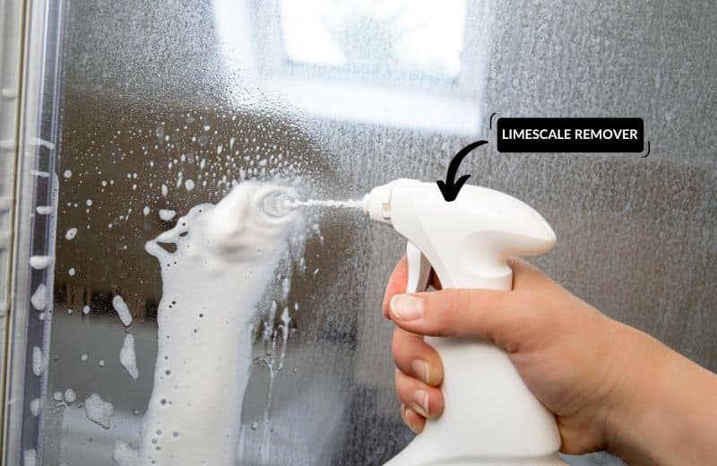 Spraying shower doors with limescale remover formula