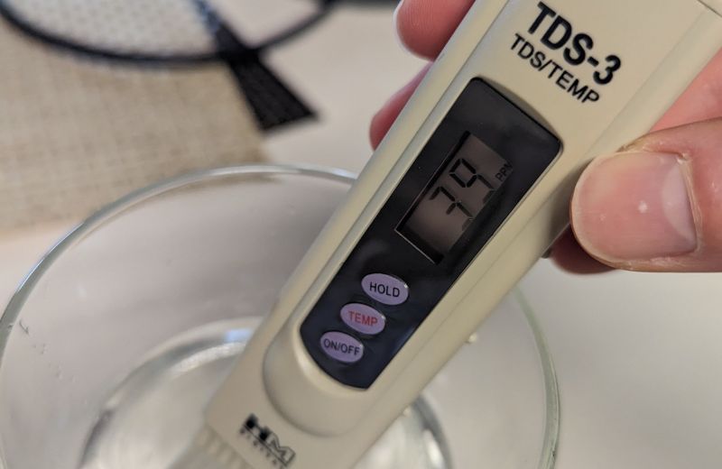 Using a handheld TDS meter to take TDS reading from glass of water