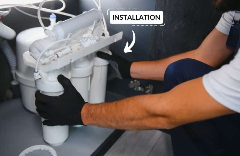 plumber installs water filter under the sink at a kitchen