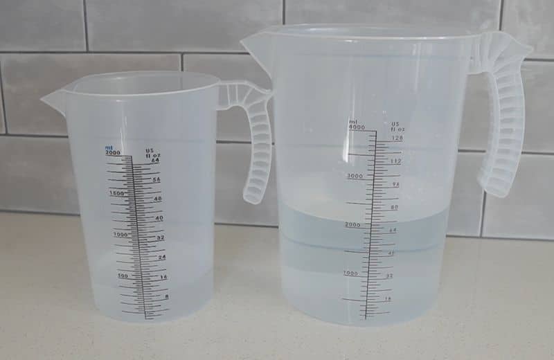 Express RO5DX Efficiency Ratio Two translucent measuring pitchers on a countertop, each partially filled with water with measurement markings visible indicating express water ro5dx product water vs waste water