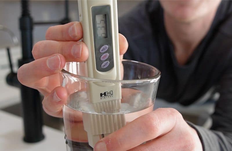 Express RO5DX TDS Measurement Brian holding a TDS meter dipped in water