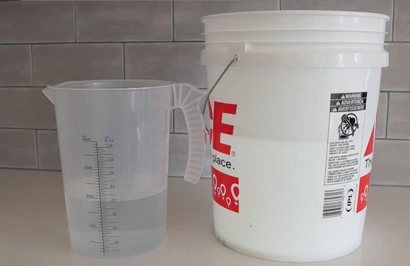 Express RO5DX Wastewater Produced one translucent measuring pitcher and a white gallon on a countertop, each partially filled with water with measurement markings visible indicating express water ro5dx product water vs waste water