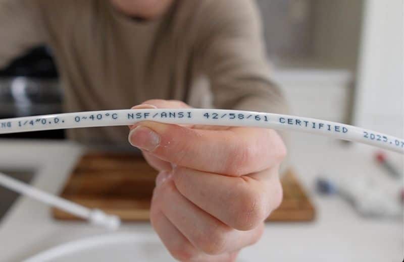 Frizzlife Tubing Label Brian holding the frizzlife tubing with “NSF/ANSI 42,53,401” printed on it