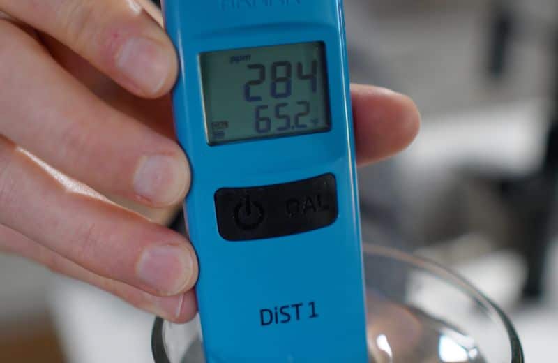 Close-up of a digital TDS meter measuring untreated water at 284 ppm before Cloud RO filtration testing.