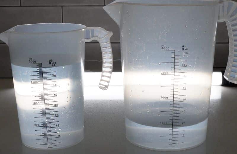 Cloud RO Efficiency Ratio Pure to waste water ratio from Cloud RO measured in two graduated measuring cups side by side. Pure water on left at 64 ounces and waste water on right at 66 ounces