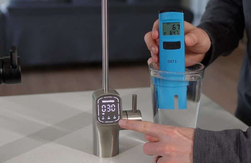 Waterdrop G3 P800 1st draw TDS reading Person testing water quality with a blue TDS meter beside the Waterdrop G3P800 reverse osmosis system faucet, showing low TDS readings in filtered drinking water.