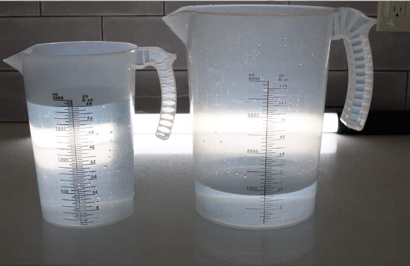 Waterdrop G3P800 Efficiency Ratio 2 Two translucent measuring pitchers on a countertop, each partially filled with water with measurement markings visible.